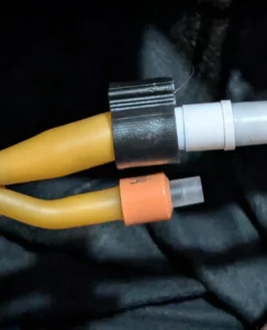 PexLock® plastic tubing clamp typically used for plumbing systems being used to clamp the end of a catheter to the plastic plug connected to silicone tubing used to collect urine drained from the bladder into a leg bag worn around the ankle.